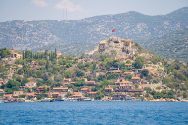 Kekova Körfezi 'nden Kalekoy kasabasının manzarası. Simena Şatosu, Türkiye 'nin çağdaş Kas kenti arasındaki Kekova Bölgesi' ndeki çarpıcı Akdeniz kıyısında yer alıyor. Antalya, Türkiye - 10 Temmuz 2023.