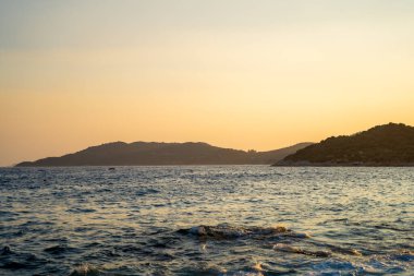Gün batımında deniz ve ada manzarası.