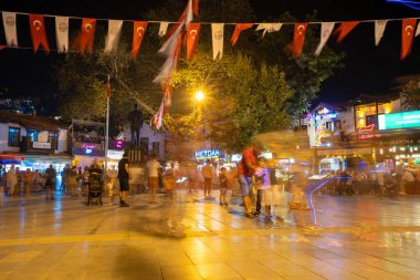 Bulanık insanlar geceleri Kas Bölge Merkezi 'nde meydanda dolaşıyordu. Antalya, Türkiye - 10 Temmuz 2023.