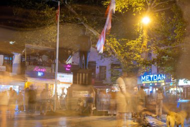 Bulanık insanlar geceleri Kas Bölge Merkezi 'nde meydanda dolaşıyordu. Antalya, Türkiye - 10 Temmuz 2023.