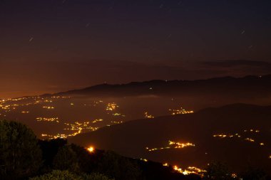 Geceleri köyün ışıkları üzerinde bulutlar ve yıldızlar..