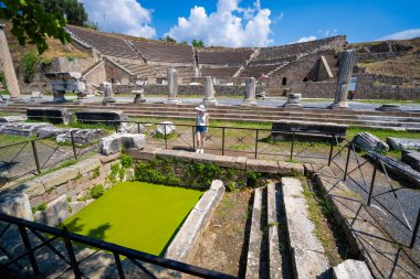 Bergama Asklepion arkeoloji sahasındaki eski havuzu ziyaret eden bir turist. Asklepion, Pergamum Acropolis 'in dışında bir tedavi merkeziydi. İzmir, Türkiye - 23 Temmuz 2023.