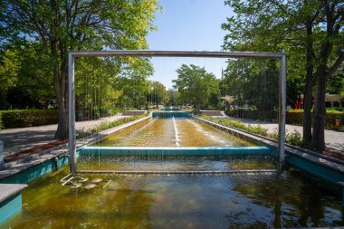 Güneşli bir sonbahar gününde Gençlik Parkı 'ndaki (Genclik Parki) çeşme. Bahçede su telleri olan güzel, modern bir havuz..