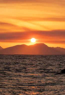 Gün batımında deniz ve ada silueti manzarası.