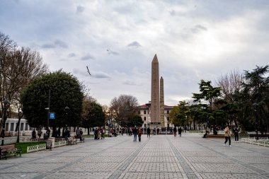 Sultanahmet ilçesinde turistler ve tarihi dikilitaşları (Yılan Sütunu, Theodosius Duvarı, Obelisk). İstanbul, Türkiye - 23 Aralık 2023.