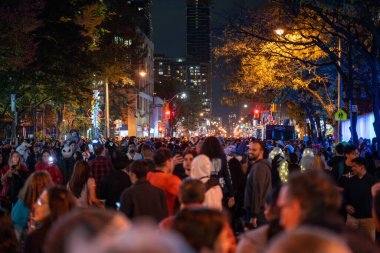 Halloween night parade on Church Street. A crowd in scary costumes walks on the street. Toronto, Canada - October 31, 2024. clipart