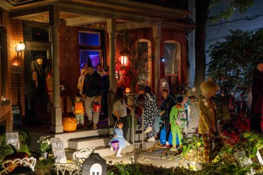 A group of children and their parents trick or treating on Halloween night. Toronto, Canada - October 31, 2024. clipart