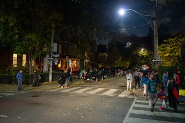 A group of children and their parents are on the street on Halloween night. Toronto, Canada - October 31, 2024. clipart