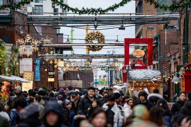 Crowd of people visiting the Christmas Village in the Distillery District. View of the Toronto Christmas Market. Toronto, Canada - December 24, 2024. clipart