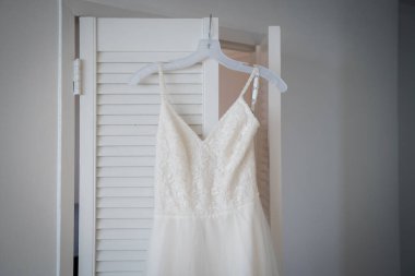 Askıdaki beyaz dantelli gelinliği kapat..