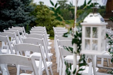 Beyaz sandalyeler ve fener süslemeleri olan açık hava düğün töreni..