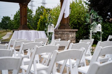 Beyaz sandalyeler ve fener süslemeleri olan açık hava düğün töreni..