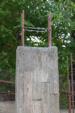 Müstakbel ev için yeşil ağaçlarla çevrili dikey beton sütunlar..