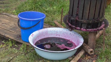 Concept for making red wine - pressing the wine with a wine squeezer - Red wine poured into a bowl.
