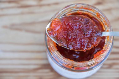 Preserving the Flavor: Pepper Jam in a Teaspoon close up with wooden background.