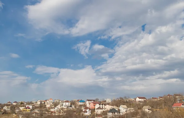 Panorama of houses on a hill against a blue sky with clouds.