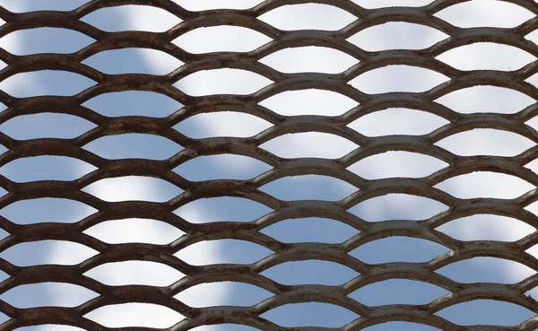 Metal mesh on a background of blue sky, closeup of photo.