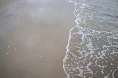 Yaz günü kumlu sahilde denizin yumuşak dalgası.