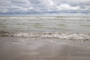 Güzel deniz manzarası, fırtınalı gökyüzü ve kumsalda dalgalar..