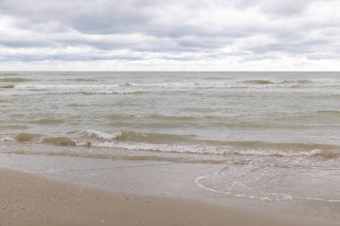 Bulutlu bir günde Adriyatik Denizi 'nde deniz dalgaları, sessiz renklerle kumlu kıyılar ve düz bir ufuk çizgisi..