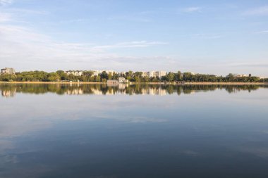 Büyücüler tarzında Chisinau Gölü ufukta ince bulutlar, göl boyunca görünen apartmanlar, açık mavi bir gökyüzü..