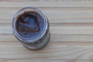 Bir kavanoz ev yapımı koyu çikolata şurubu açık ahşap bir masada, üst tarafta..