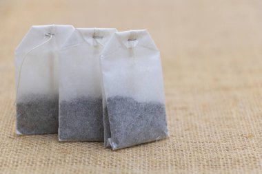 Three tea bags on the table, close-up of paper tea bags with black and gray coffee inside.