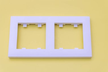 Beyaz plastik dikdörtgen çerçeve, elektrik tepsisi için iki pencere, üst manzara, sarı arkaplan.