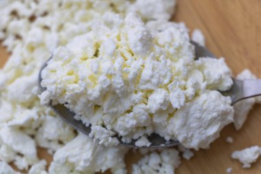 Taze parçalanmış beyaz peynir kaşıkta, pişirmeye ya da servis etmeye hazır..