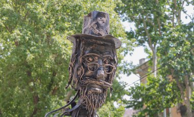 Sakallı ve bıyıklı, hurda metalden şapka takan yaşlı bir adamın heykeli..