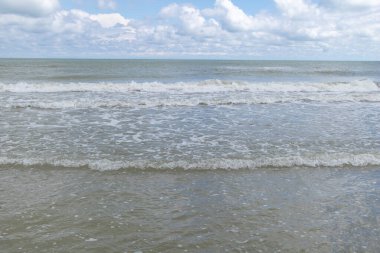 Huzurlu Deniz Dalgaları Yumuşak Bulutlu Parlak Mavi Gökyüzünün Altında Yavaşça Kıyıya Yuvarlanıyor.