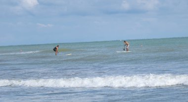 Rimini, İtalya - 2005 Ağustos 2023 Aktif İnsanlar Sahilde Güneşli bir Yaz Günü 'nde Deniz Dalgalarında Sörf ve Kürek Çekiyor.