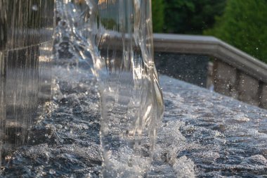Şehir Parkı 'nda Damlayan Damlalar ve Güneş Işığı Yansımaları Olan Modern Çeşmeden Akan Suyun Yakın Çekimi.