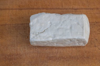 Kırsal ahşap yüzeyde beyaz parçalanmış peynir bloğu.