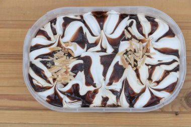 Kırsal ahşap yüzeyinde badem dilimli vanilyalı ve çikolatalı dondurma..