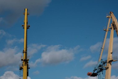 Yüksek bir binanın inşaatı sırasında vinç inşaatı. Ağır bir yük taşıyor. Kule vinçleri bir ev inşa ediyor. Beton bina yapım aşamasında. İnşaat alanı