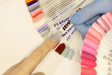 Manikür ustasının işyeri. Bir kuaför uzmanı müşterisiyle çalışır. Steril eldiven takan bir tırnak teknisyeni. El bakımı, oje başvurusu. Güzellik salonu manikürü ve pedikür..