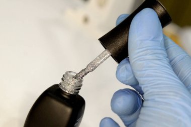 Manikür ustasının işyeri. Bir kuaför uzmanı müşterisiyle çalışır. Steril eldiven takan bir tırnak teknisyeni. El bakımı, oje başvurusu. Güzellik salonu manikürü ve pedikür..