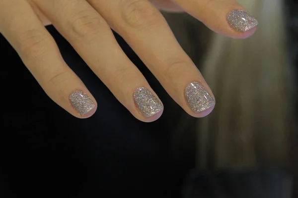 The work of a manicurist. Silver nail polish, festive manicure with glitter