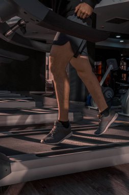 Spor salonunda bir adam koşu bandında koşuyor. Kapalı kardiyo. Spordan dolayı kalp atışları hızlandı.