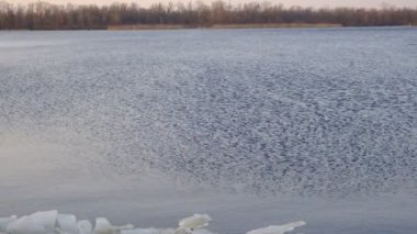 blocks of ice near the river bank. Ice drift of ice floes on rivers and lakes under the influence of current or wind. Accumulation of melt water between the bank and the edge of the ice on the river