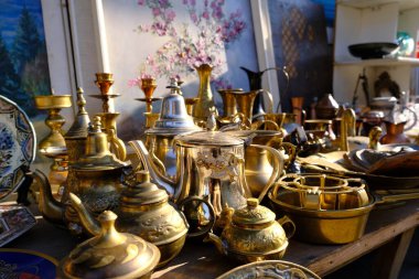 October 30, 2021. Ukraine, Dnipro, Flea market. Brass, bronze vases and vintage sugar bowls. Painting in watercolor behind the dishes