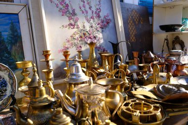 October 30, 2021. Ukraine, Dnipro, Flea market. Brass, bronze vases and vintage sugar bowls. Painting in watercolor behind the dishes