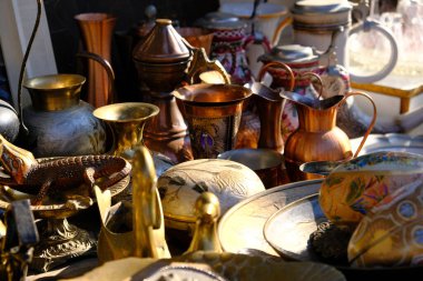 October 30, 2021. Ukraine, Dnipro, Flea market. Brass, bronze vases and vintage sugar bowls. Painting in watercolor behind the dishes