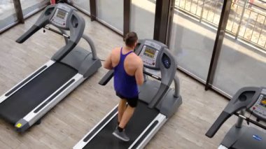 A man on a treadmill is engaged in cardio training. Workout in the gym. Body workout, leg muscles strengthening. Weight loss from sports