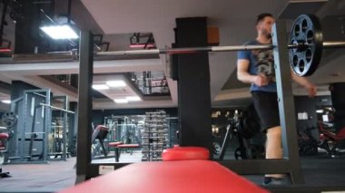 February 21, 2023 Ukraine, Dnipro.Barbell bench press. A young athlete on a simulator in a supine position loads the muscles of his arms and chest. Training of muscle groups of the upper body. gym