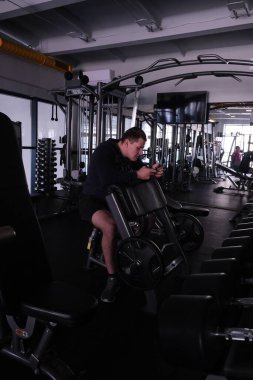 Spor salonundaki spor aletleri. Stylish spor sahasındaki adam. Ağır mandallı genişleticiler ve simülatörler. Benç presi, anaerobik ve aerobik egzersizler..