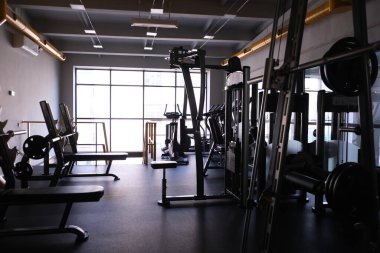 Sports equipment in the gym. Stylish bright sports space. Expanders and simulators with heavy dumbbells.Bench press, sport for a strong body and weight loss clipart