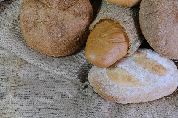 loaves of bread from the bakery in the store. Burlap and straw with pastries. Various loaves, baguettes. Rye, buckwheat, bran, gluten-free, wheat in a confectionery. private bakery.