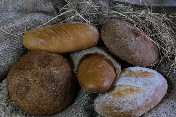 loaves of bread from the bakery in the store. Burlap and straw with pastries. Various loaves, baguettes. Rye, buckwheat, bran, gluten-free, wheat in a confectionery. private bakery.